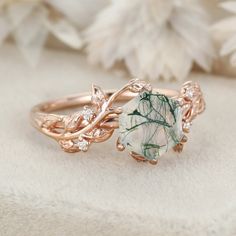 two gold rings with green and white stones on top of each other next to flowers