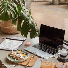 an open laptop computer sitting on top of a table next to a plate of food