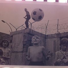 black and white photograph of three children playing with a soccer ball