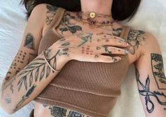 a woman with tattoos on her chest and arms is laying in bed wearing a brown top