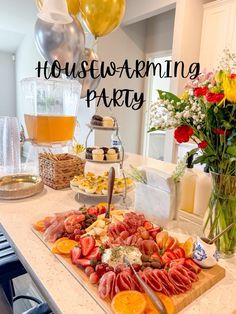 a table filled with food and balloons in the background that says housewarming party