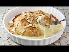 a white bowl filled with food covered in sauce and almonds on top of a table