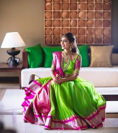 a woman in a green and pink dress sitting on the floor next to a couch