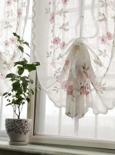 a potted plant sitting on top of a window sill next to a curtain