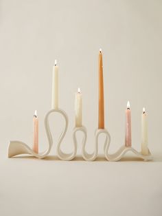 five candles are lined up in the shape of a long candle holder with four smaller ones on each side