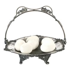 three white eggs are in an ornate metal bowl on a stand with marbled edges