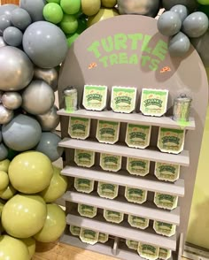 there are some green and gray balloons on the shelf next to each other in front of a sign that says turtle treats