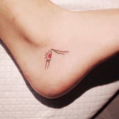 a small tattoo on the foot of a woman with a red heart in her hand