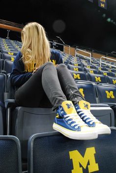 a woman is sitting on the bleachers in michigan university's athletic stadium