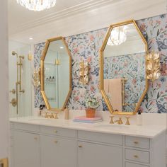 a bathroom with floral wallpaper and gold mirrors