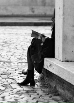 a person sitting on the ground reading a book