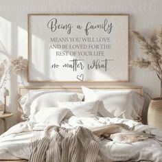 a bed with white sheets and pillows next to a wooden framed sign that says being a family means you will love and be loved for the rest of your life no matter