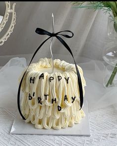 a birthday cake with white frosting and black ribbon around it's edges that say happy birthday