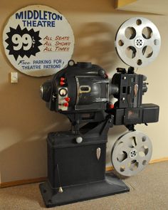 an old movie projector sitting in front of a sign