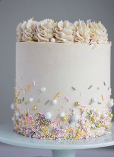 a large white cake with sprinkles and confetti on the top