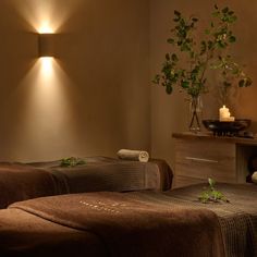 two massage beds with towels on them in a room next to a plant and candles