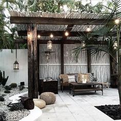 an outdoor living area with couches, tables and lights on the ceiling is surrounded by palm trees