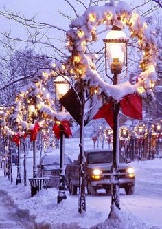 a street light covered in snow next to a tree with red bows and lights on it