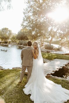 a bride and groom standing in front of a lake