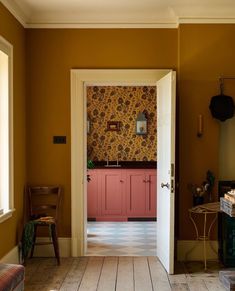 an open door leading into a room with yellow walls and pink cabinets on the wall