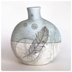 a vase with a feather painted on it