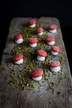 there are many small red and white candies on the wooden board with green sprinkles