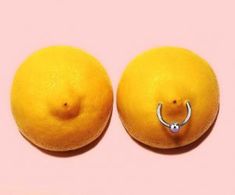 two oranges with nose rings on them against a pink background, one has an oxen in the middle