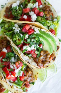 three tacos with meat, tomatoes and avocado garnished with cilantro