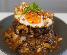 a plate topped with an egg and mushrooms covered in gravy