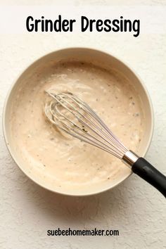 a bowl filled with sauce and whisk on top of a white tablecloth