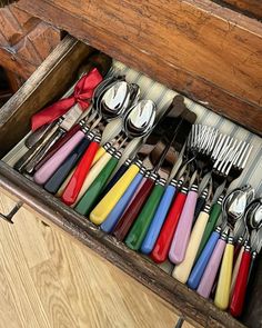 a wooden box filled with lots of different colored utensils