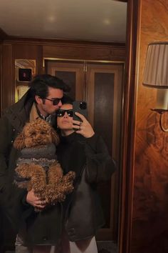 a man taking a selfie in front of a mirror with a dog on his lap