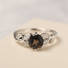 an engagement ring with a brown stone surrounded by white diamonds on top of a card