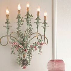 a chandelier hanging from the side of a wall next to a vase with flowers on it