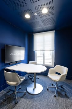 a room with blue walls and chairs around a white table in front of a flat screen tv