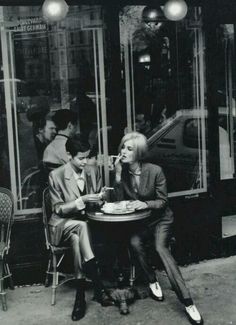 black and white photograph of two people sitting at a table in front of a restaurant