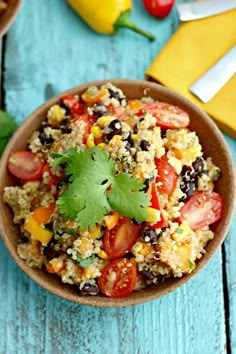 a bowl filled with rice and vegetables on top of a blue wooden table next to yellow napkins