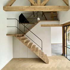 a wooden staircase in an empty room with white walls and wood beams on the ceiling