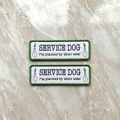 two green service dog tags sitting on top of a marble counter next to each other