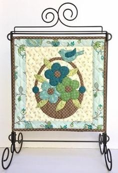 an iron stand holding a quilt with flowers on it