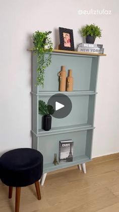 a blue bookcase sitting on top of a wooden floor next to a black stool