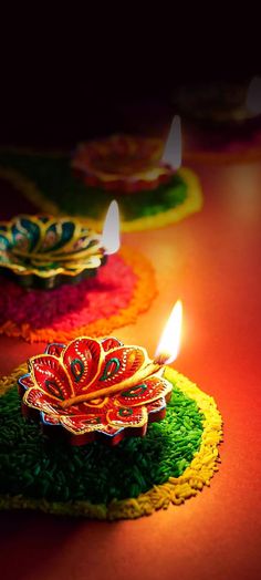 three colorful candles sitting on top of green grass