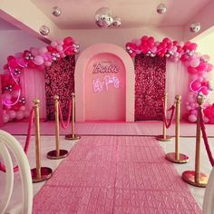 a pink and gold party setup with balloons, ropes, and decorations on the walls