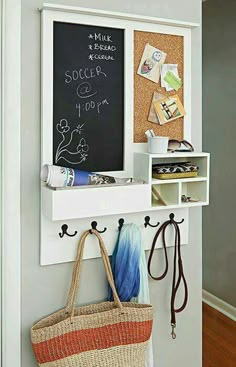 a wall mounted chalk board with two hooks and a purse hanging on the back of it