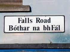 a street sign that reads falls road both na bh fal on the side of a building