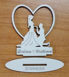 a wedding cake topper in the shape of a heart with a bride and groom holding hands