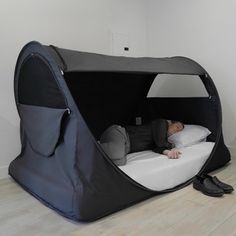 a man laying on top of a bed in a room next to a white wall