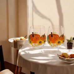 two wine glasses sitting on top of a white table next to a bowl of food