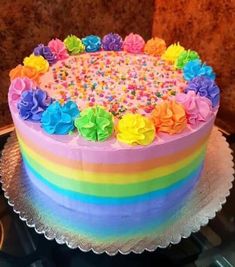 a rainbow cake with sprinkles and flowers on top