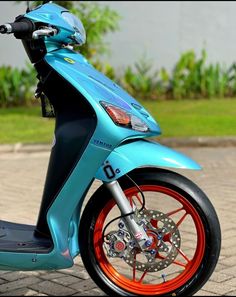 a blue scooter with orange rims parked on the street